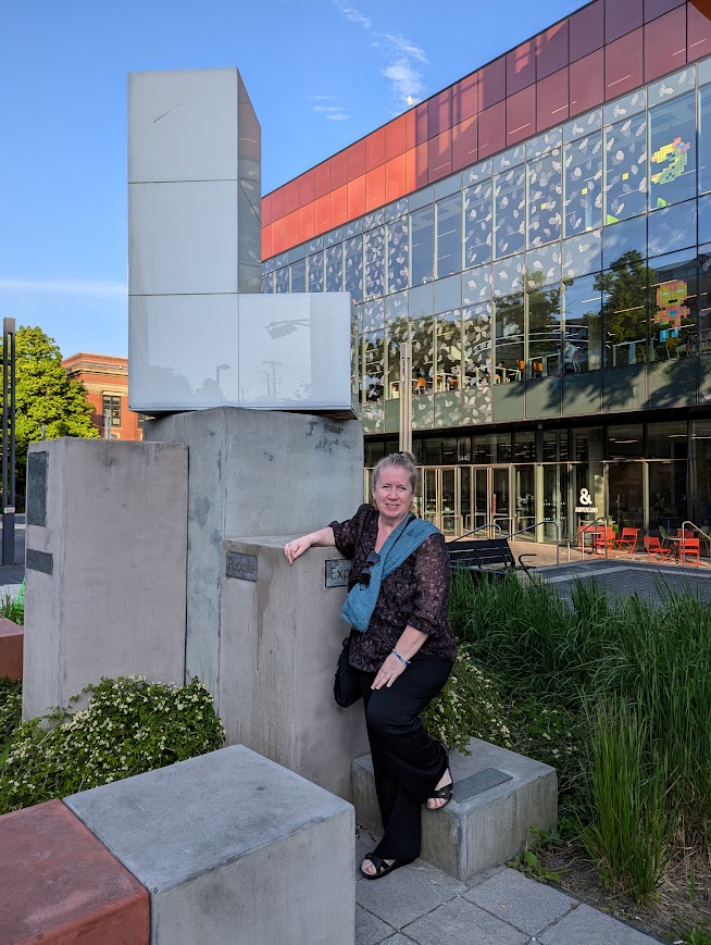 Blonde tourist beside the big L of the Halifax Central Library building